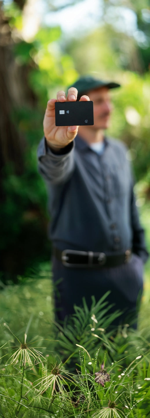 Man standing in a sunlit garden holding the black Vantamo tracker card up to the camera