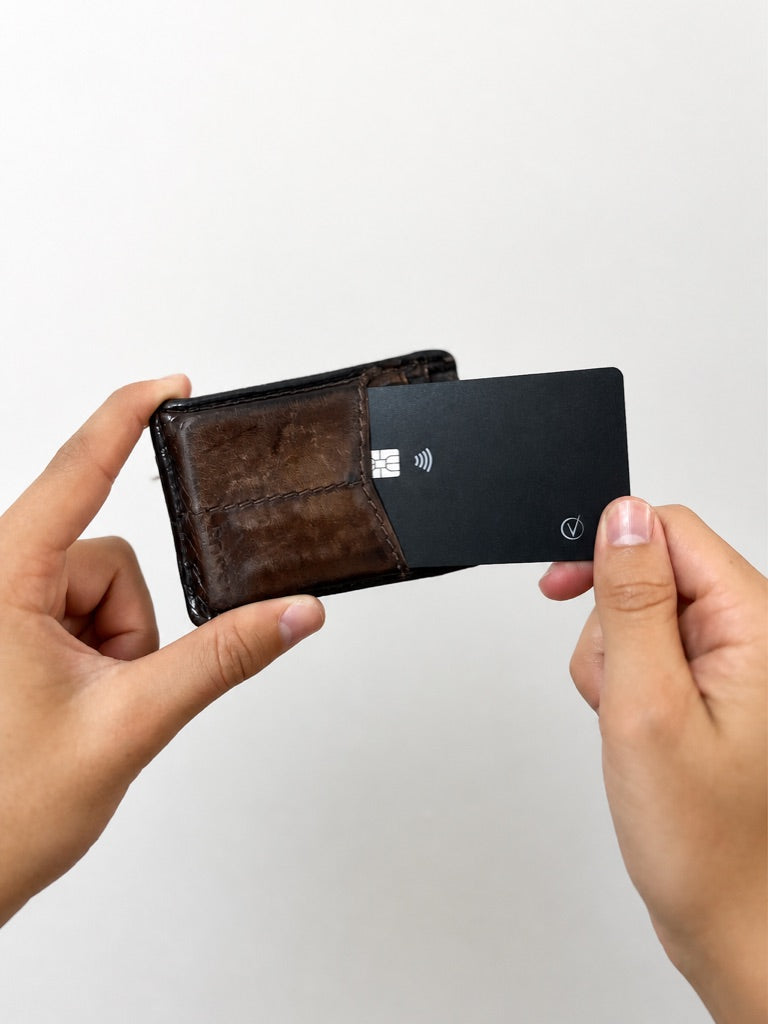 Vantamo tracker card held next to a slim leather wallet