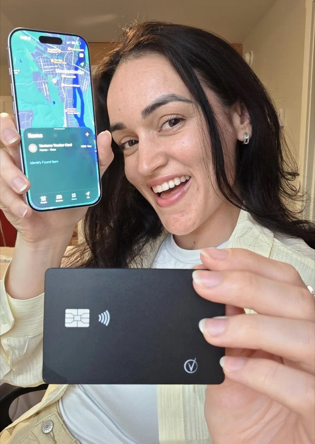 Smiling woman holding the Vantamo tracker card beside her iPhone showing its location in Find My